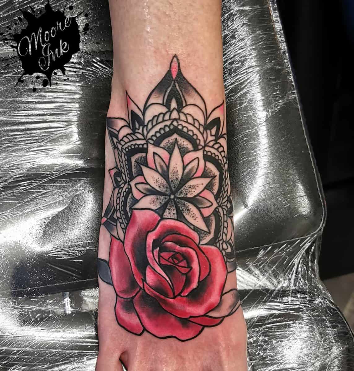 Forearm tattoo with a red rose and detailed black mandala background