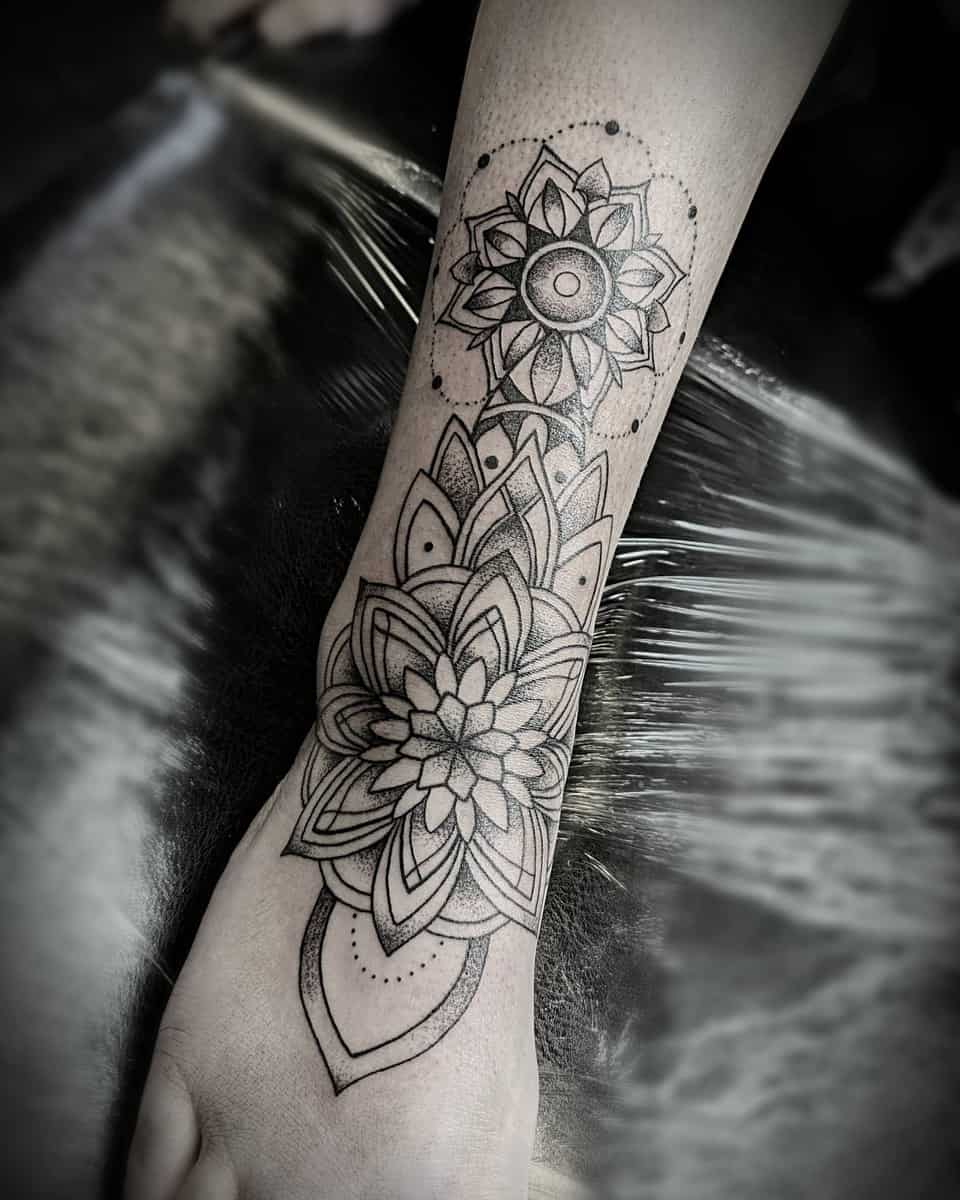 Black and grey floral mandala tattoo on the wrist and forearm