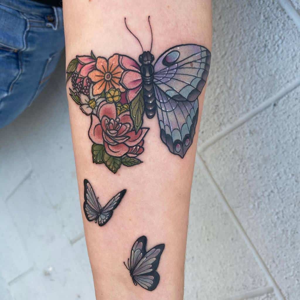 Forearm tattoo of a butterfly with flowers, featuring a striking blue butterfly accompanied by two smaller butterflies in flight