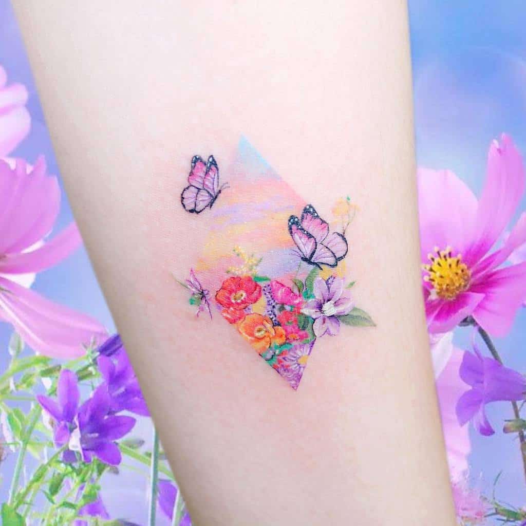 Geometric tattoo with flowers and butterflies on an arm, surrounded by pink and purple flowers