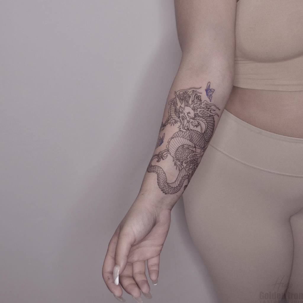 Arm tattoo with a detailed dragon and butterfly design
