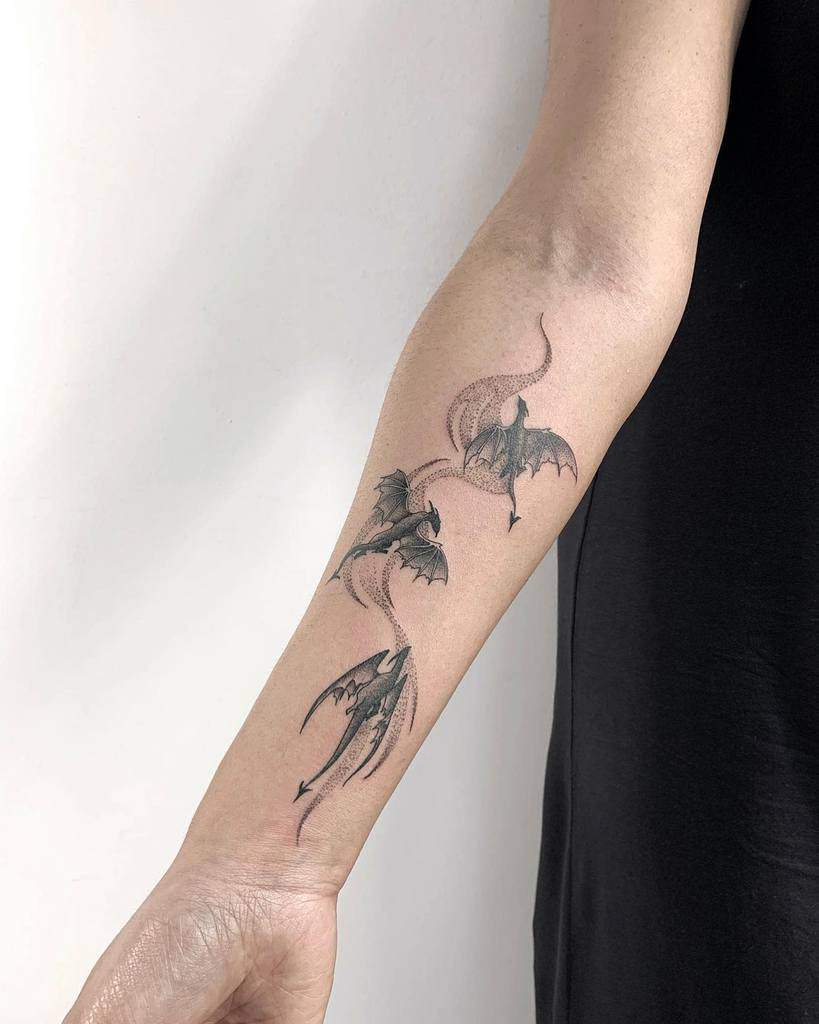 Forearm tattoo of three dragons in a dynamic, swirling design
