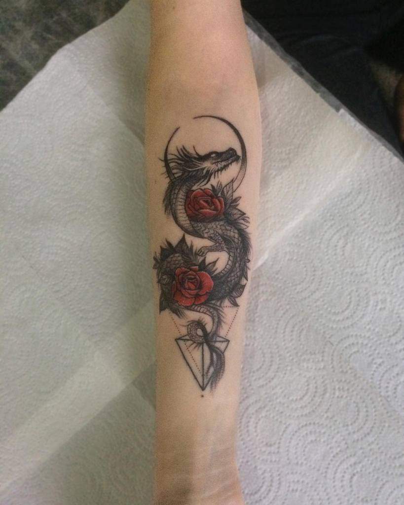 Tattoo of a dragon intertwined with red roses on a woman's forearm