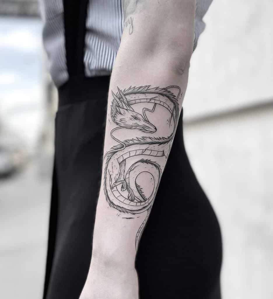 Arm with a dragon tattoo in black ink, featuring intricate details and shading
