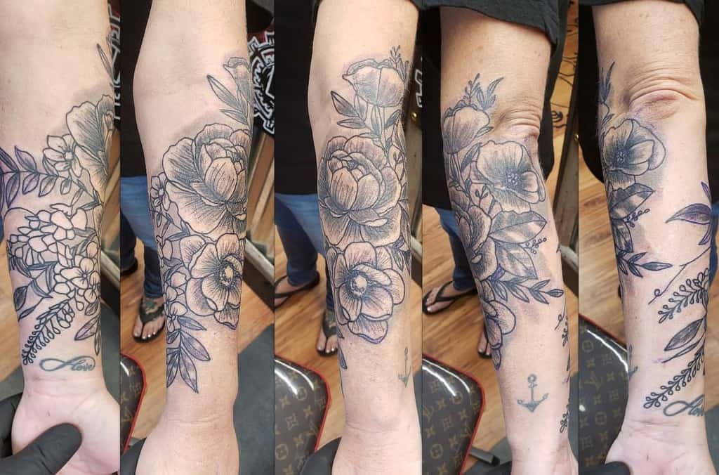 Forearm tattoo featuring detailed flowers and leaves