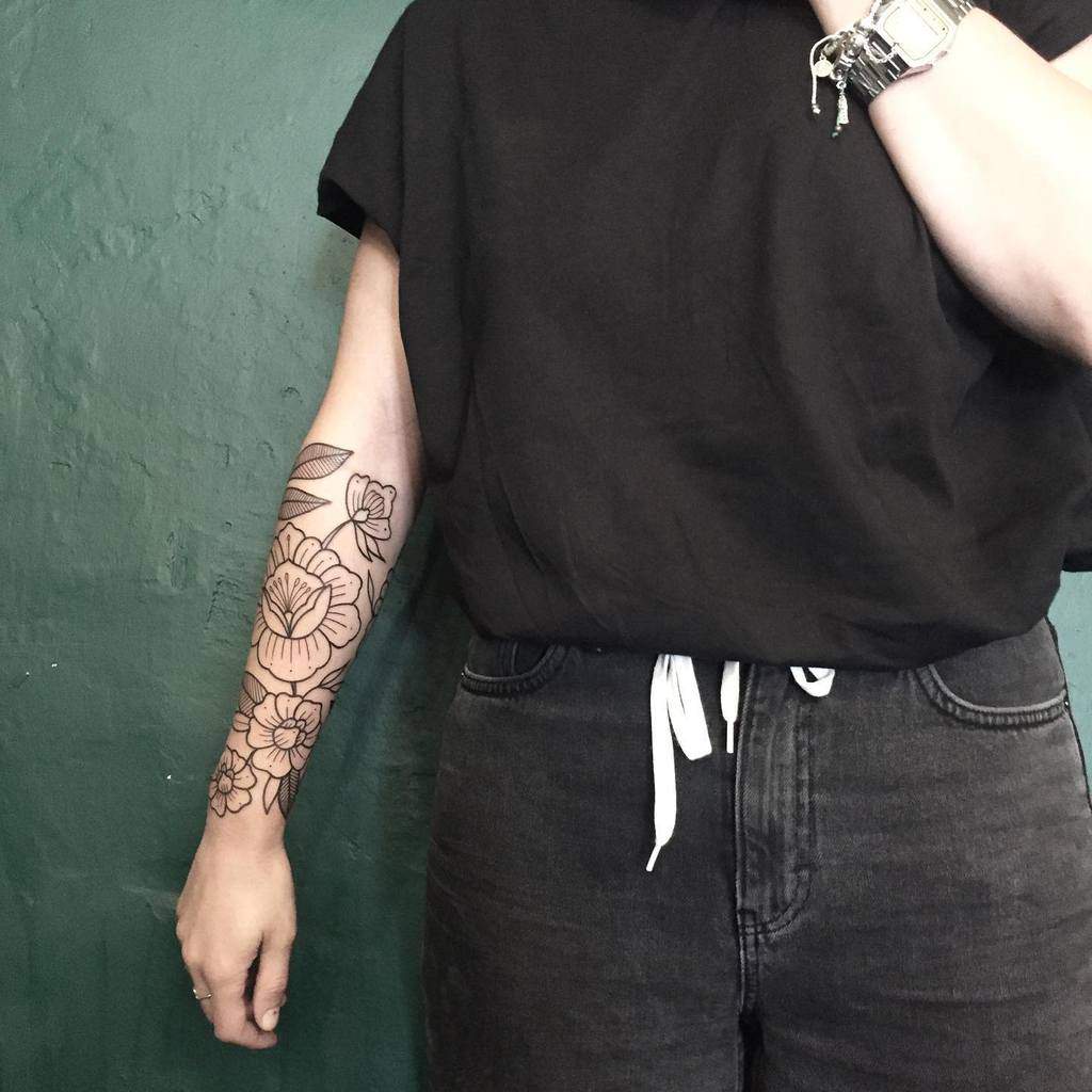 Woman with a floral line tattoo on her forearm