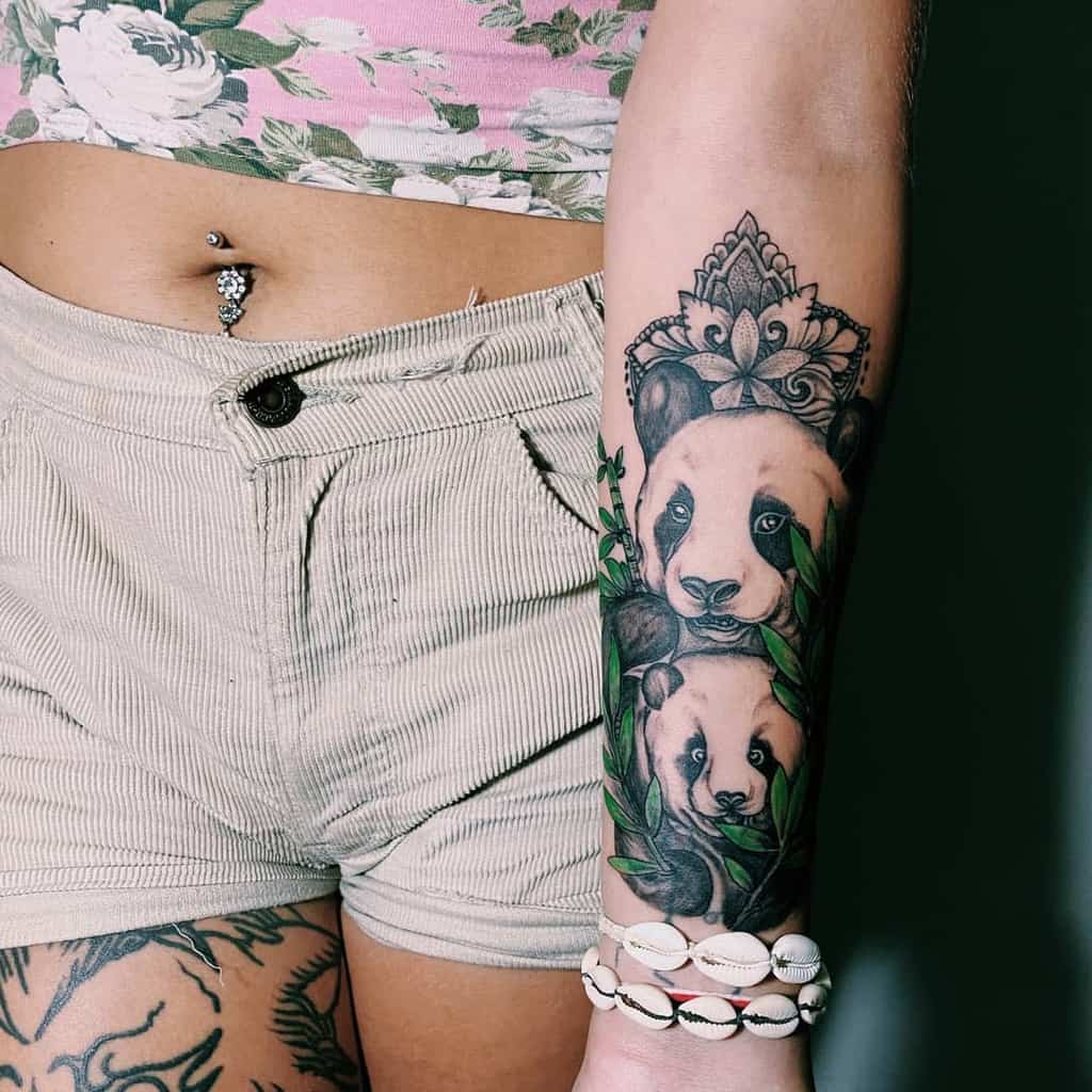 Forearm tattoo of pandas with leaves and a floral design above