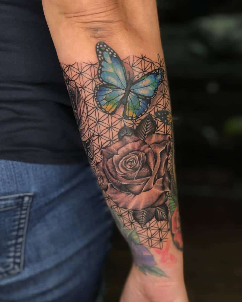Forearm tattoo of a butterfly and rose with geometric patterns in the background