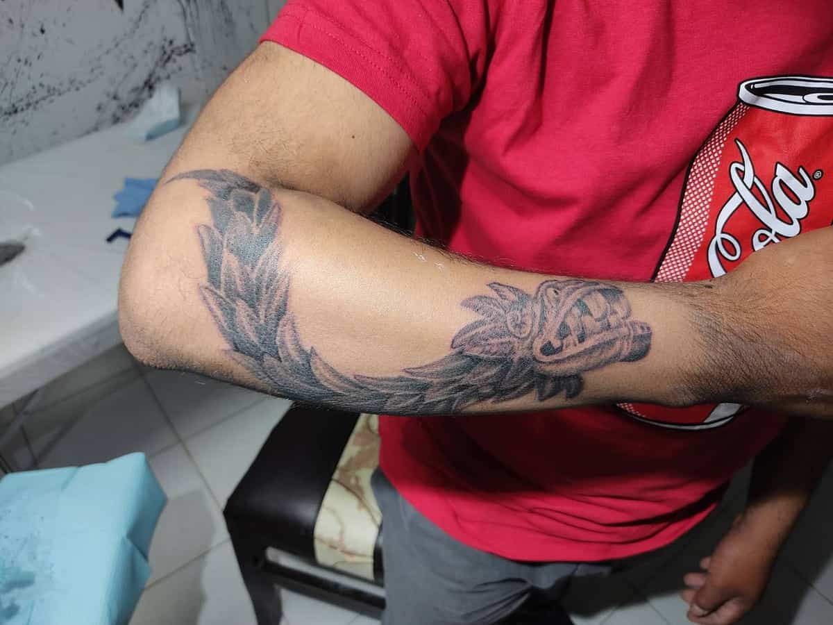 Forearm Quetzalcoatl tattoo featuring a feathered serpent design wrapping around the arm