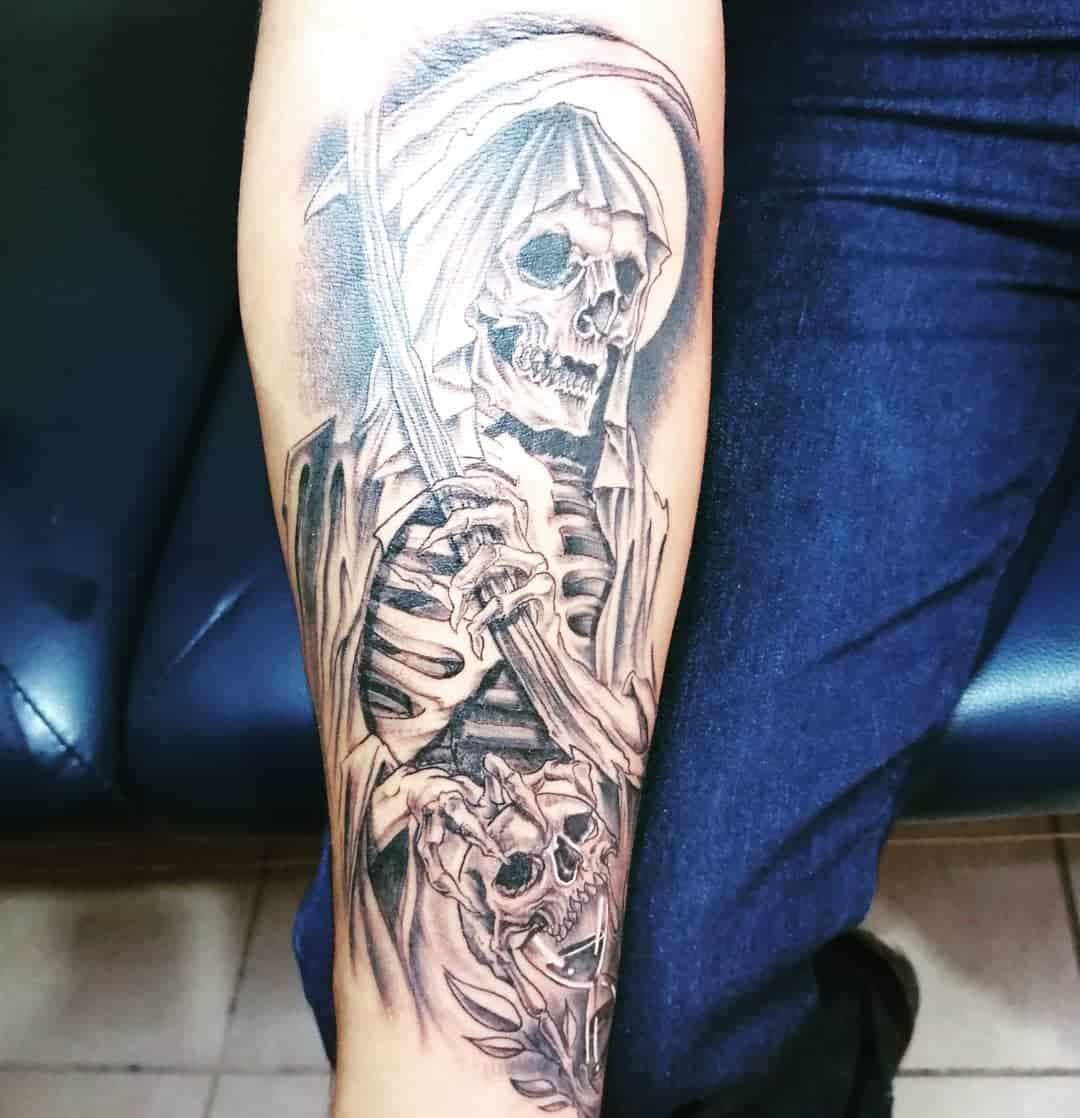 Black-and-grey tattoo of Santa Muerte wielding a scythe, symbolizing death and transition, with a skull below