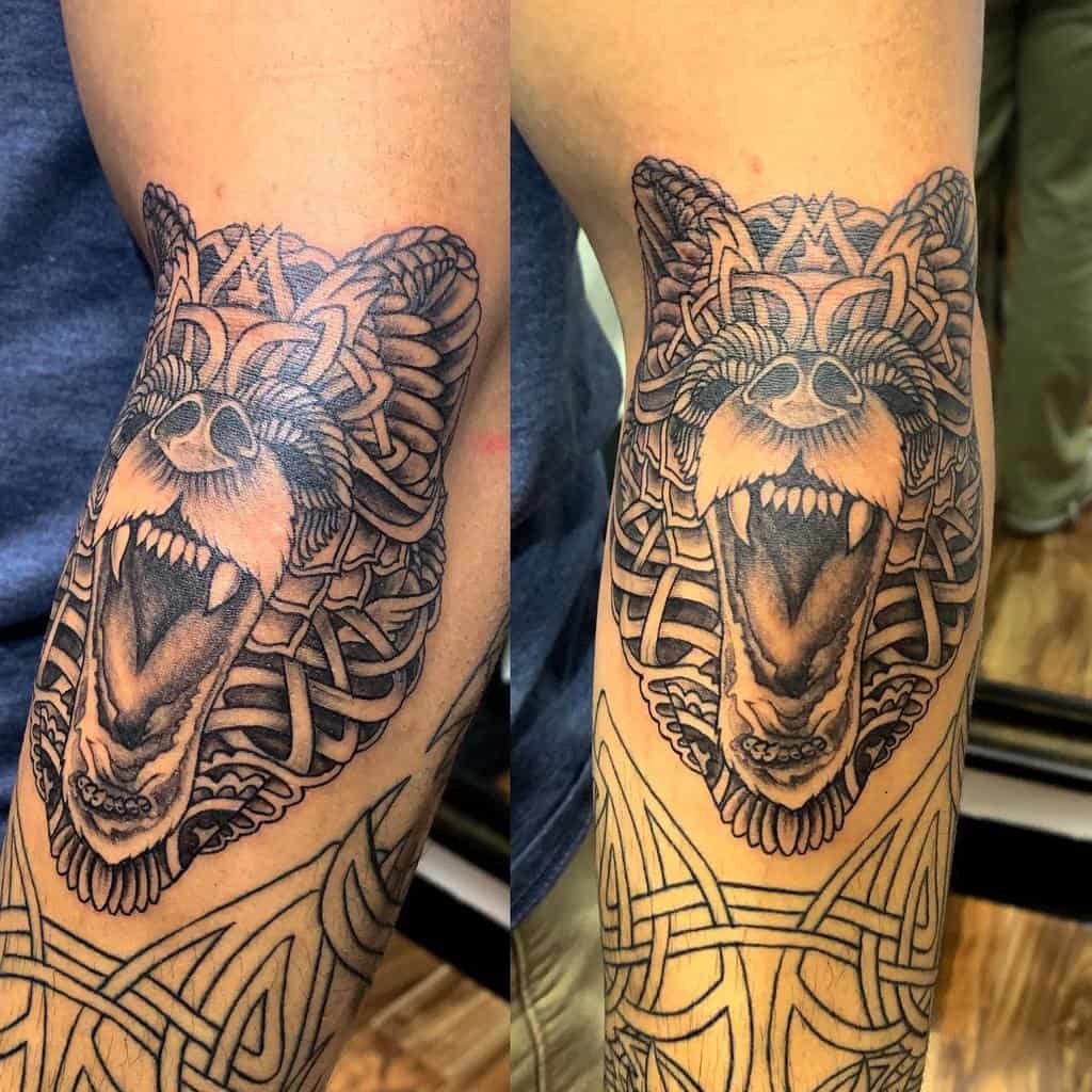 An elaborate tattoo of a roaring bear adorned with tribal patterns on an arm