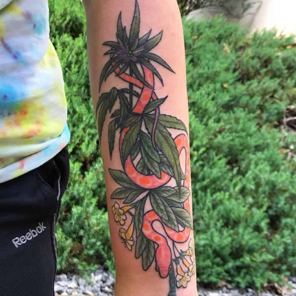 Vibrant forearm tattoo featuring an orange snake wrapped around honeysuckle flowers and lush leaves
