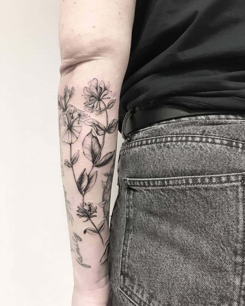 Elegant forearm sleeve tattoo with soft shading, showcasing intricate honeysuckle blooms and foliage
