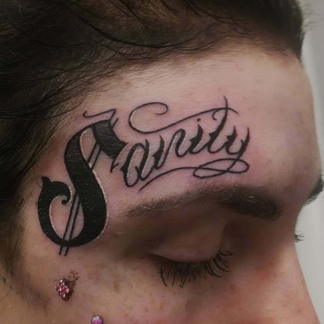Close-up of a forehead tattoo that reads "Sanity" near a closed eye