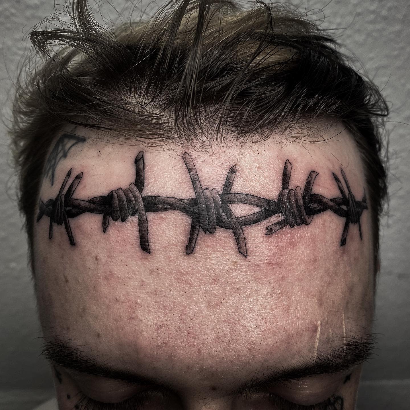 Man with a barbed wire tattoo across his forehead