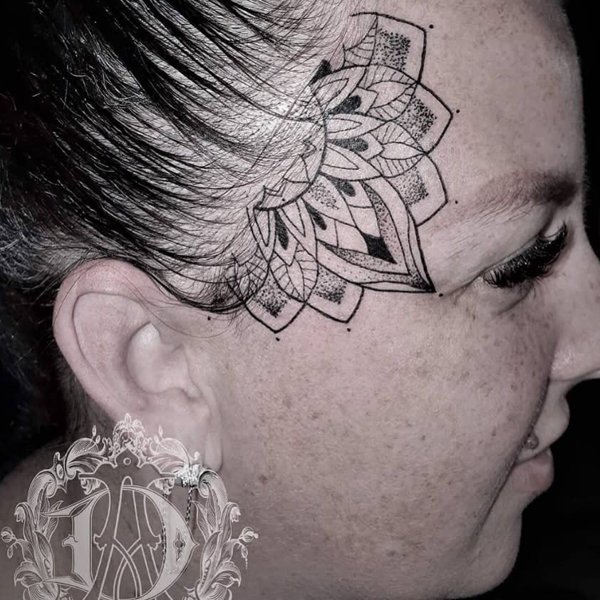 Woman with an intricate mandala tattoo on the side of her head near her hairline