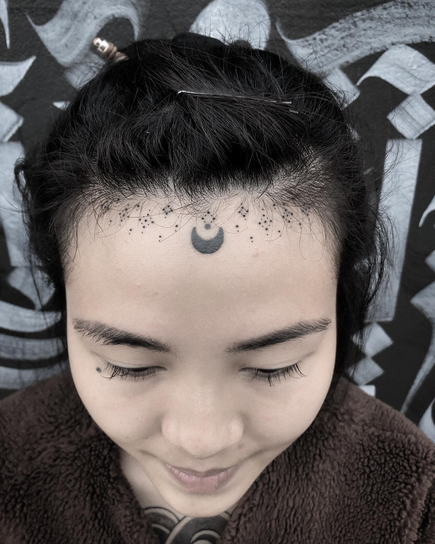 Intricate moon and dots forehead tattoo on a young woman