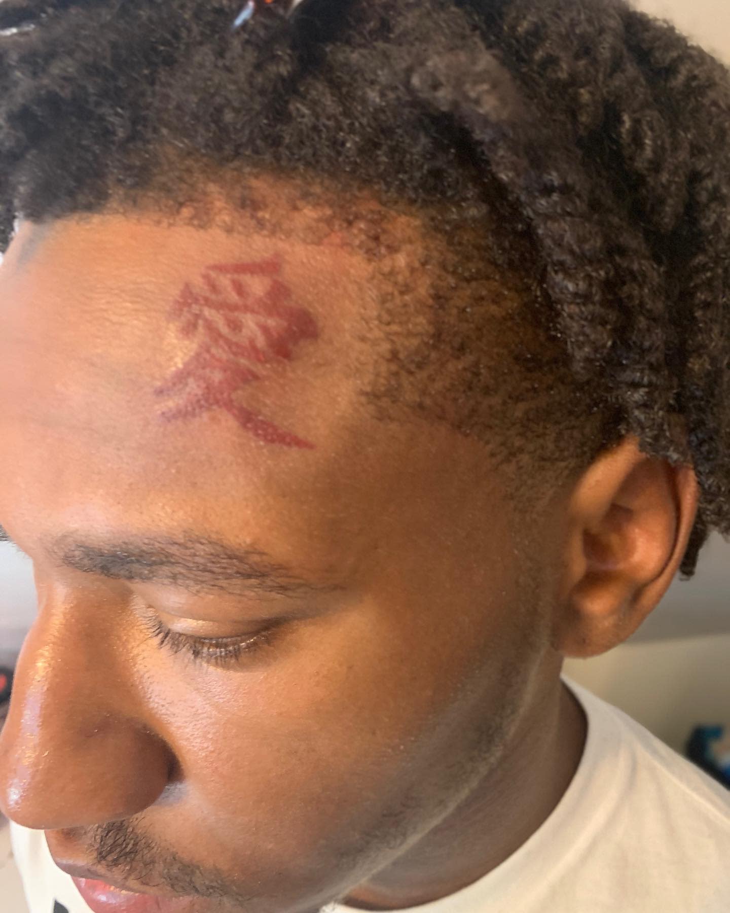 Red Chinese letters tattoo on the forehead