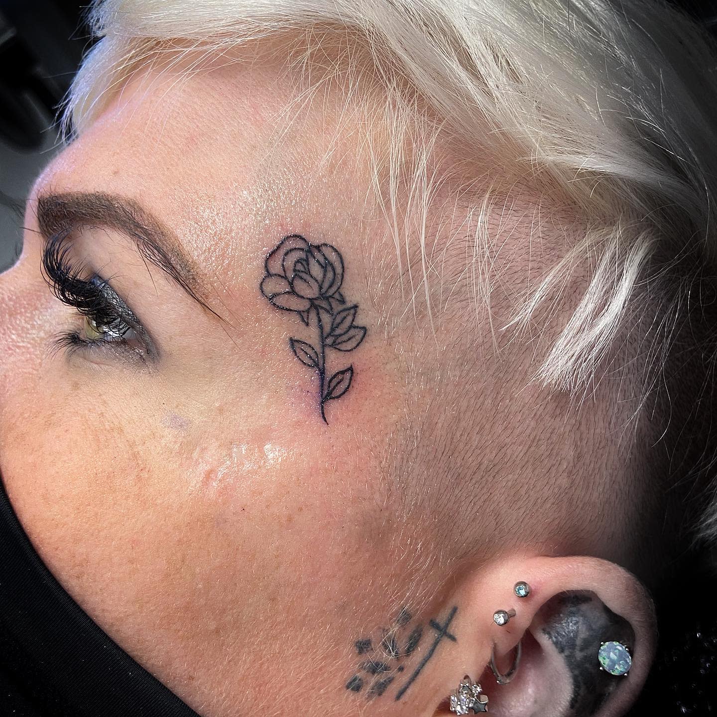 A tattoo of a rose on the side of head