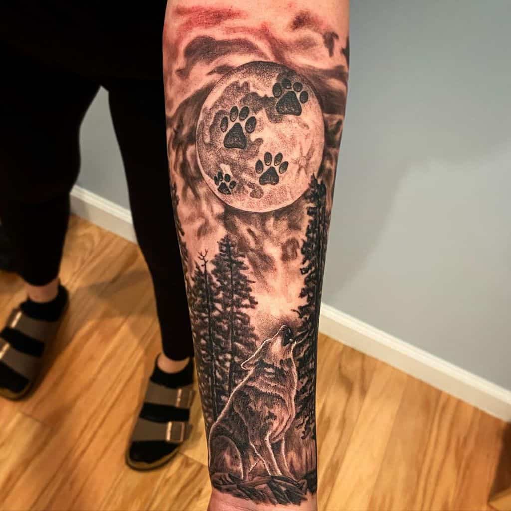Tattoo of a wolf howling at a moon with paw prints, surrounded by trees