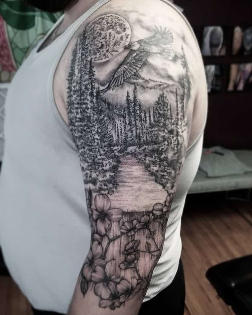 A person with a detailed forest and nature-themed tattoo on the upper arm