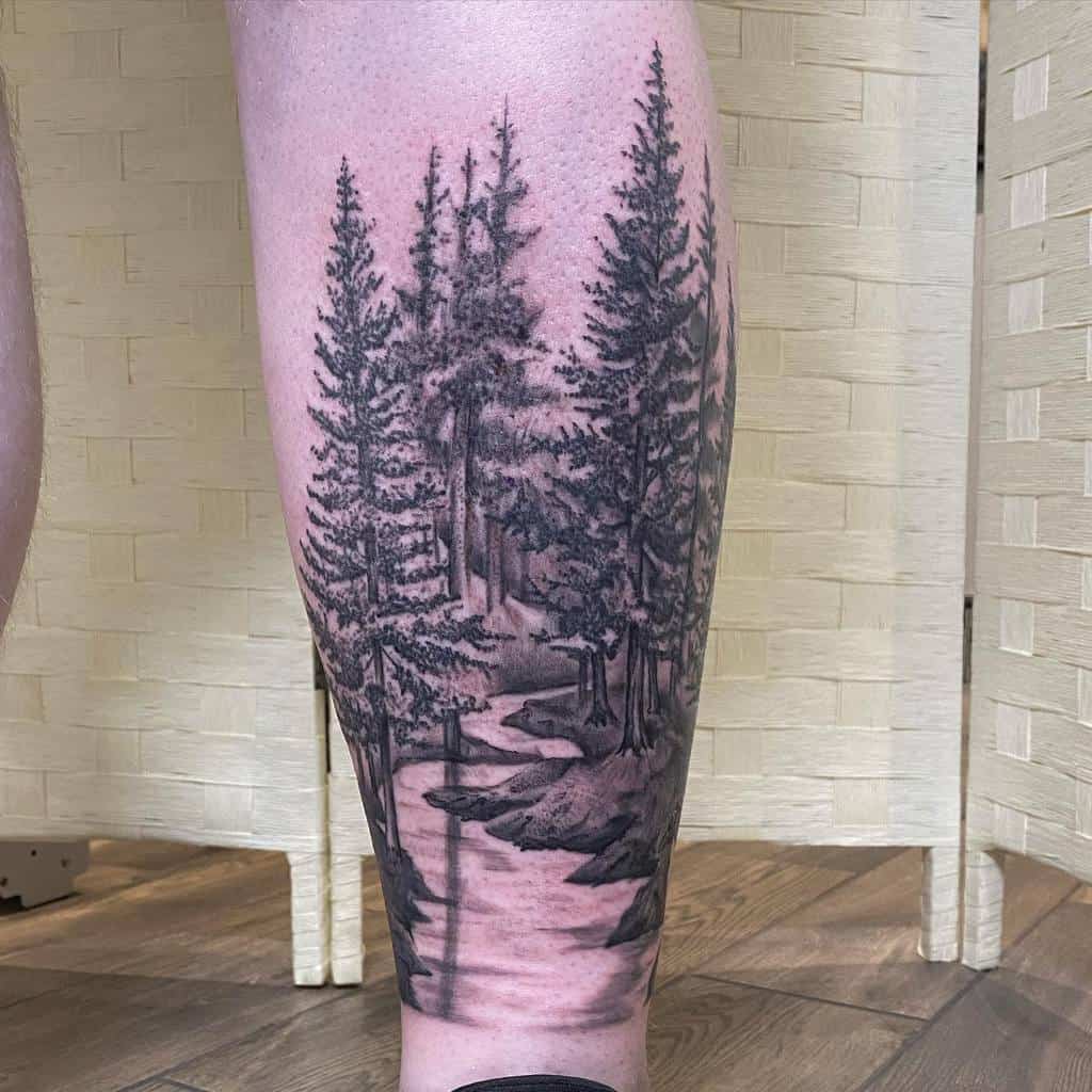 Tattoo on leg of a forest scene with the silhouette of pine trees and a winding path