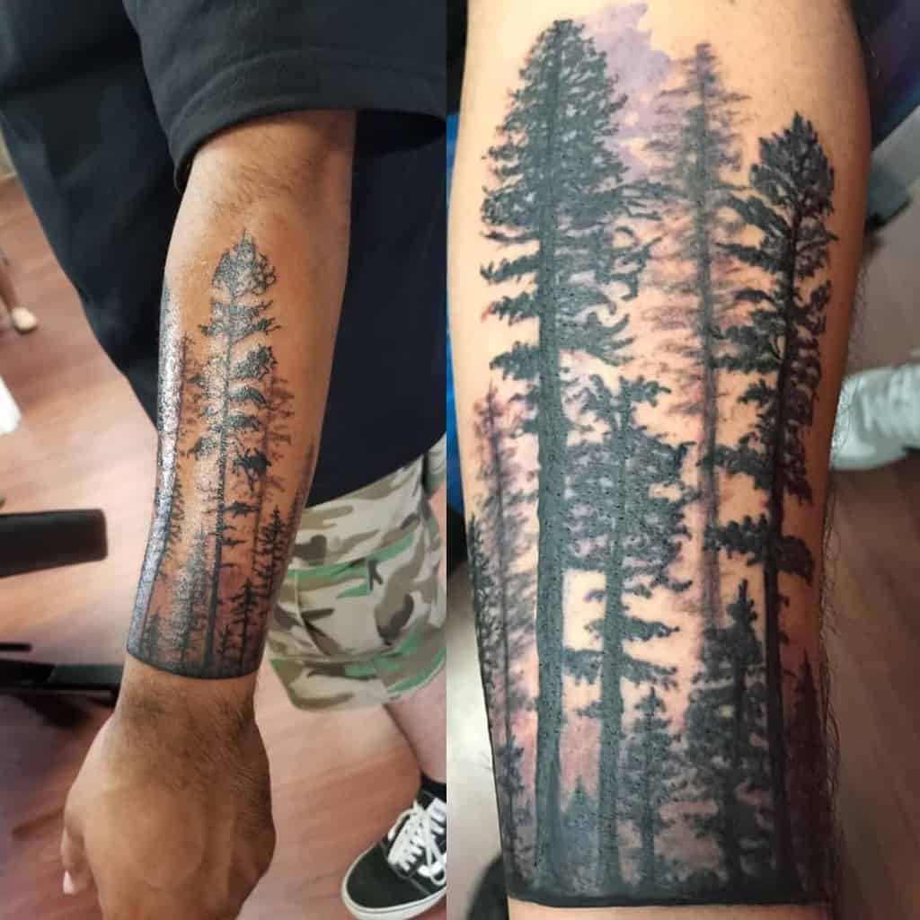 Tattoo of tall, detailed pine tree silhouettes on a person's forearm