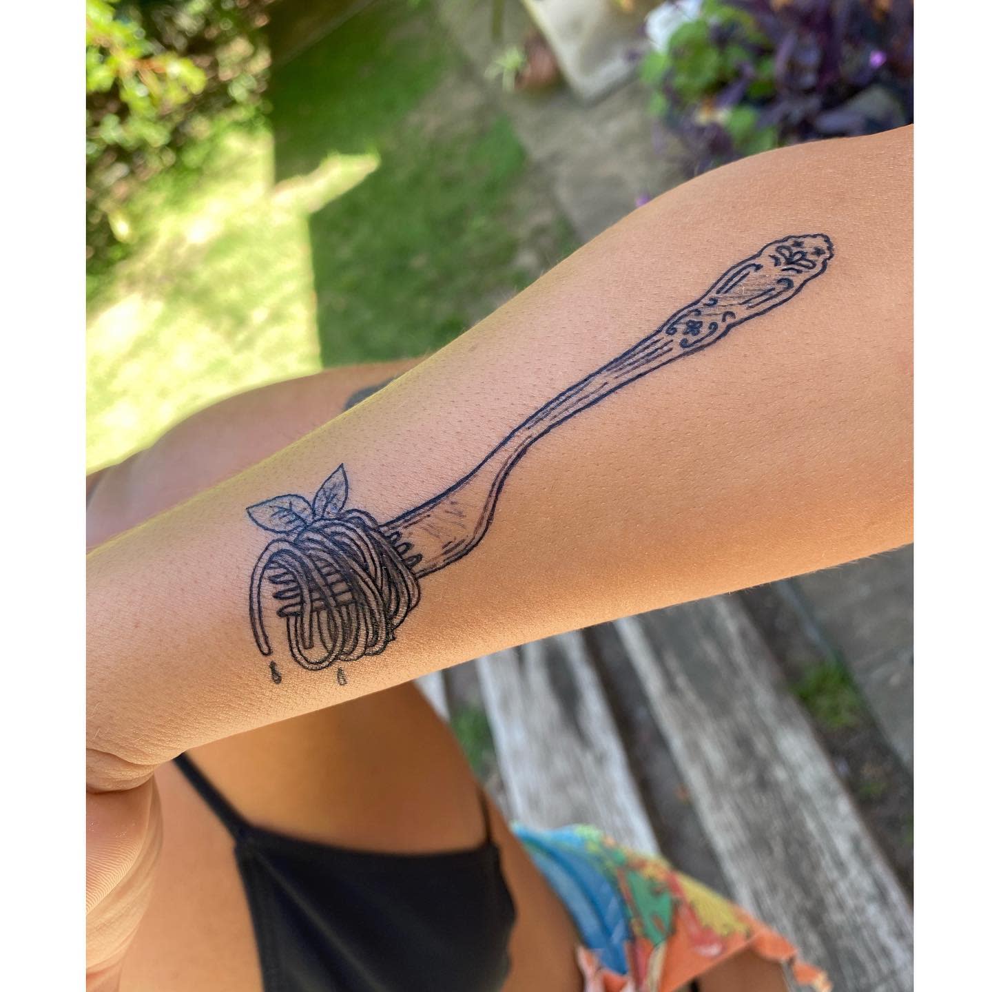 A tattoo of a fork twirling spaghetti on an arm