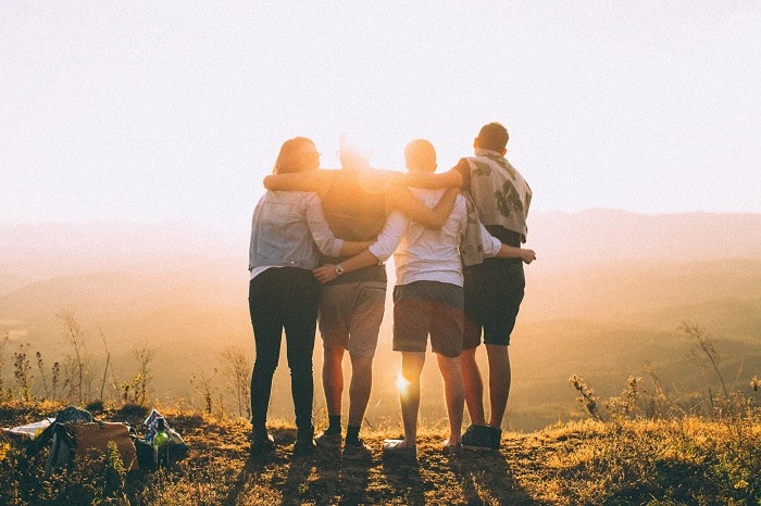 Friends Standing On Hill At Sunset