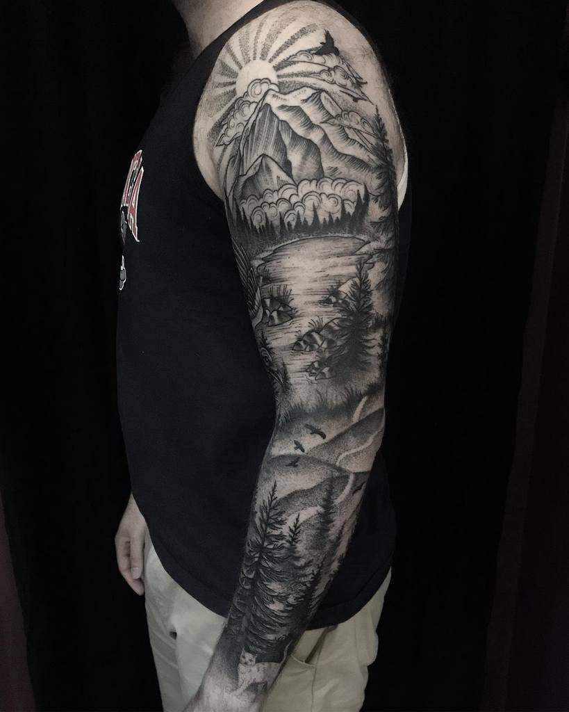 Full-sleeve black-and-grey tattoo featuring a mountain sunrise, a serene forest landscape, and a flowing river, encapsulating the beauty of nature