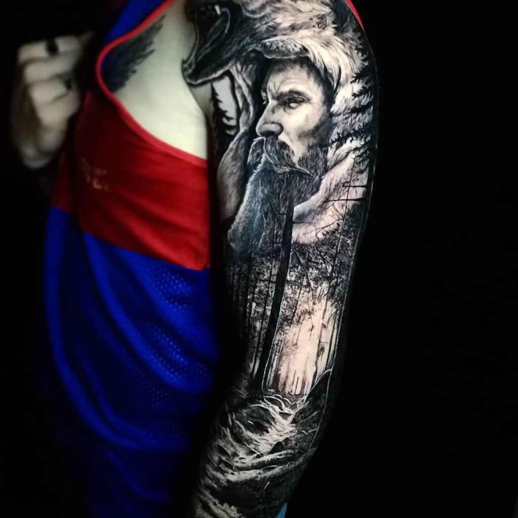 Arm tattoo with a Viking warrior, forest, and wolf design