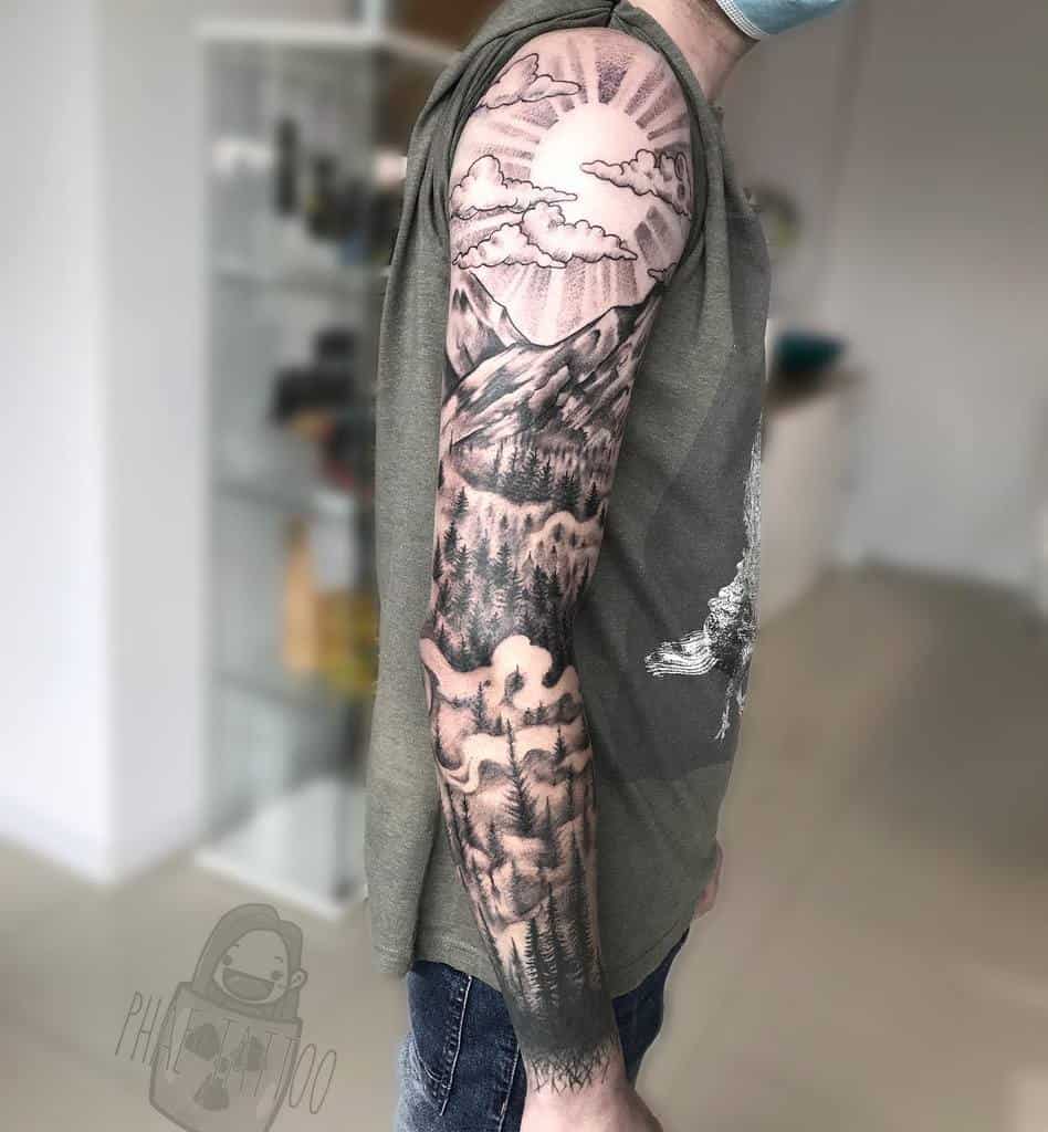 Man with a detailed mountain landscape tattoo sleeve on his arm