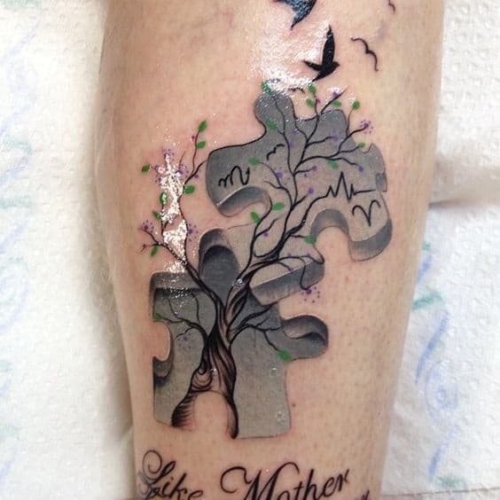 Full color calf tattoo of a puzzle piece with a tree, birds, Scorpio symbol and an EKG reading.