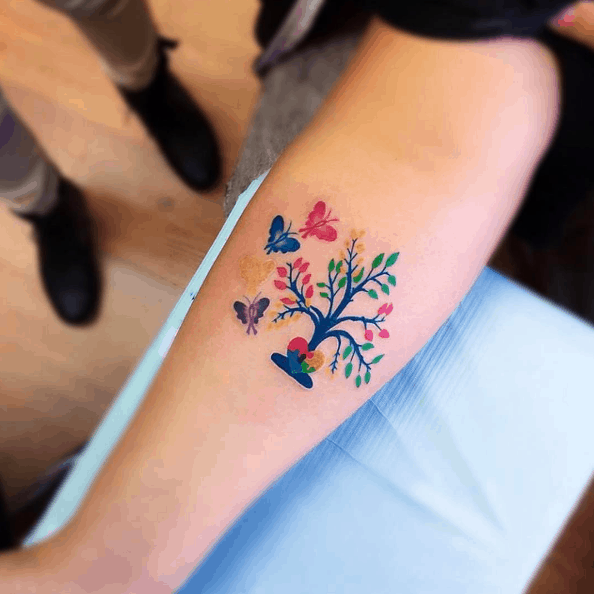 Full color forearm tattoo of a tree growing from Autism Awareness Puzzle heart with four butterflies.