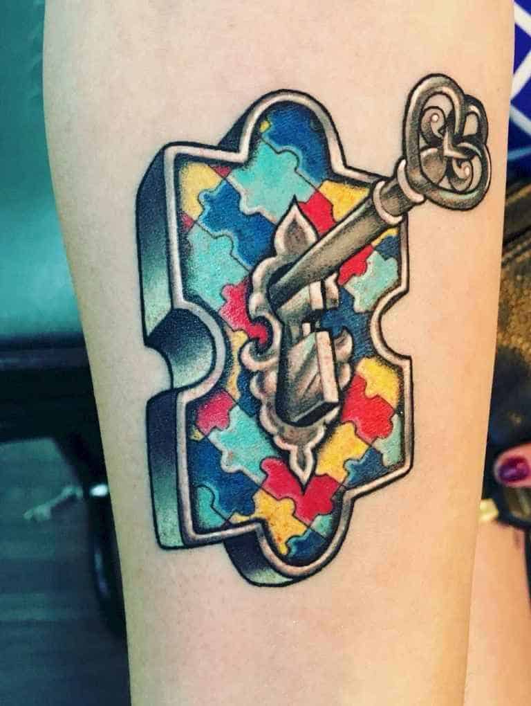 Full color tattoo of a multi-colored puzzle piece lock with a skeleton key in the key hole.