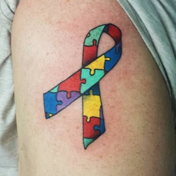 Full color upper-arm tattoo of Autism Awareness Puzzle ribbon.