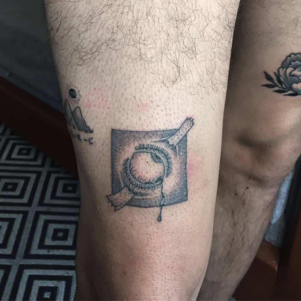 Tattoo of a single needle condom wrapper on a person's leg