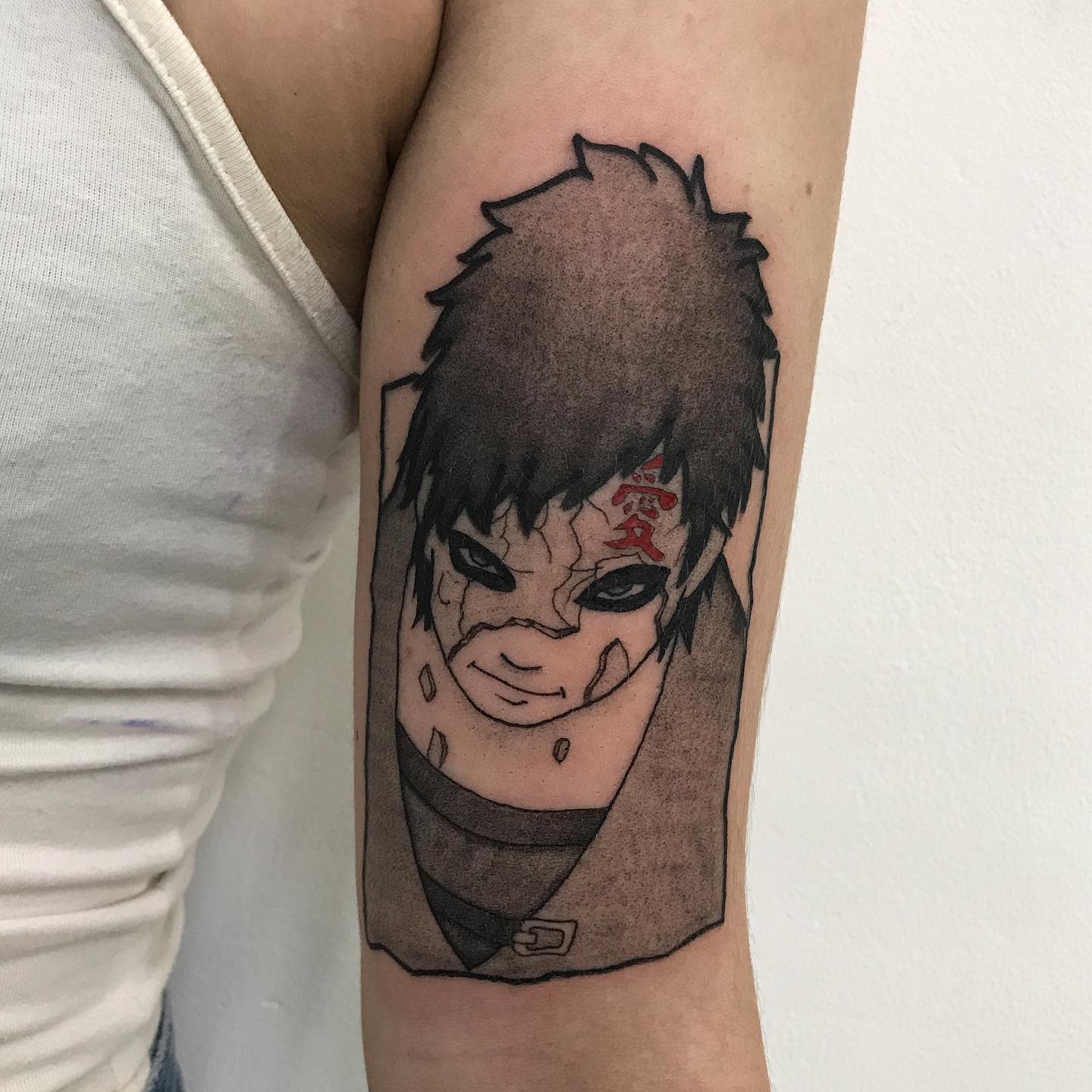 Arm tattoo of a black-haired anime character Gaara with a mark on their forehead and intense eyes