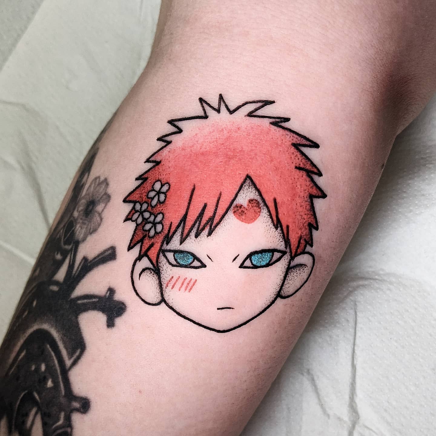 Tattoo of an anime character Gaara with red hair and blue eyes on an arm