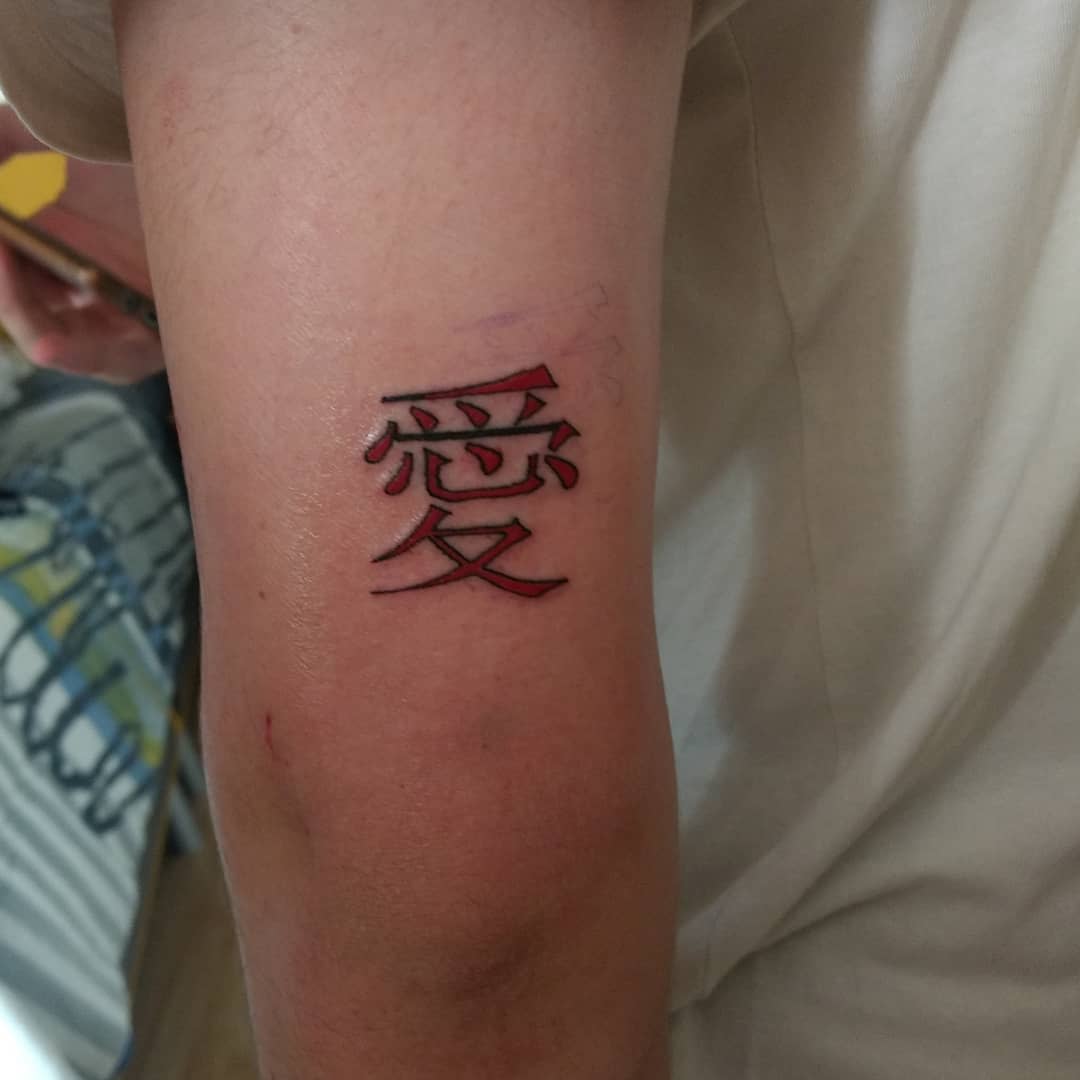 A tattoo with red Chinese characters on an upper arm