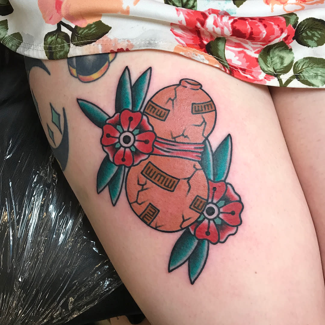 Tattoo of two red vases with flowers and leaves on a thigh