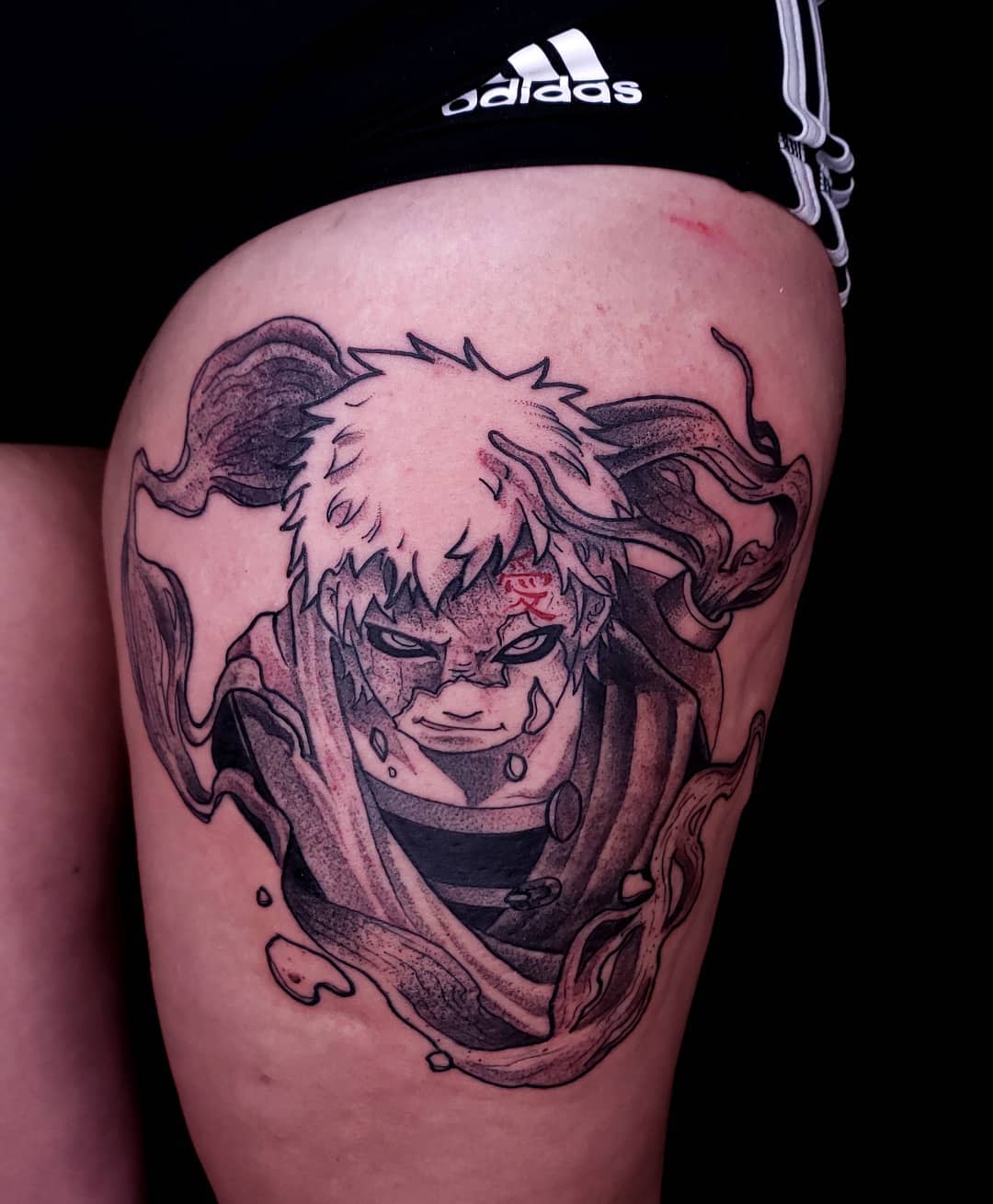 Tattoo of an intense anime character Gaara with white hair and dark ink swirls on upper thigh