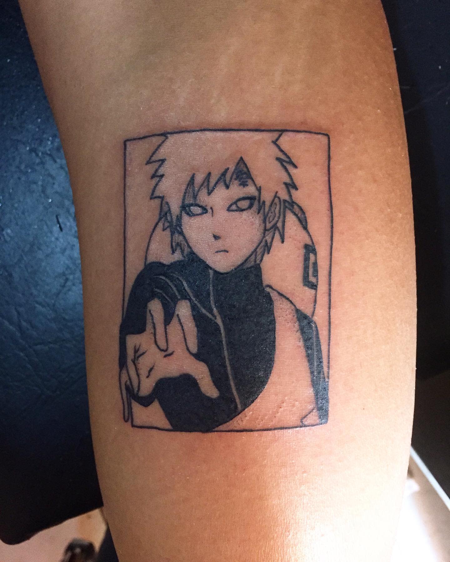 A tattoo featuring an anime character with spiky hair and a serious expression