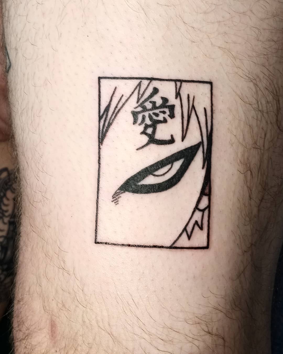 Tattoo showing anime character's eye and part of face within a square frame with kanji symbols
