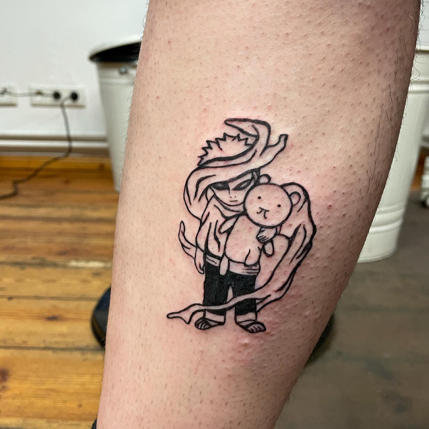 Tattoo of a stylized character holding a teddy bear on someone's leg