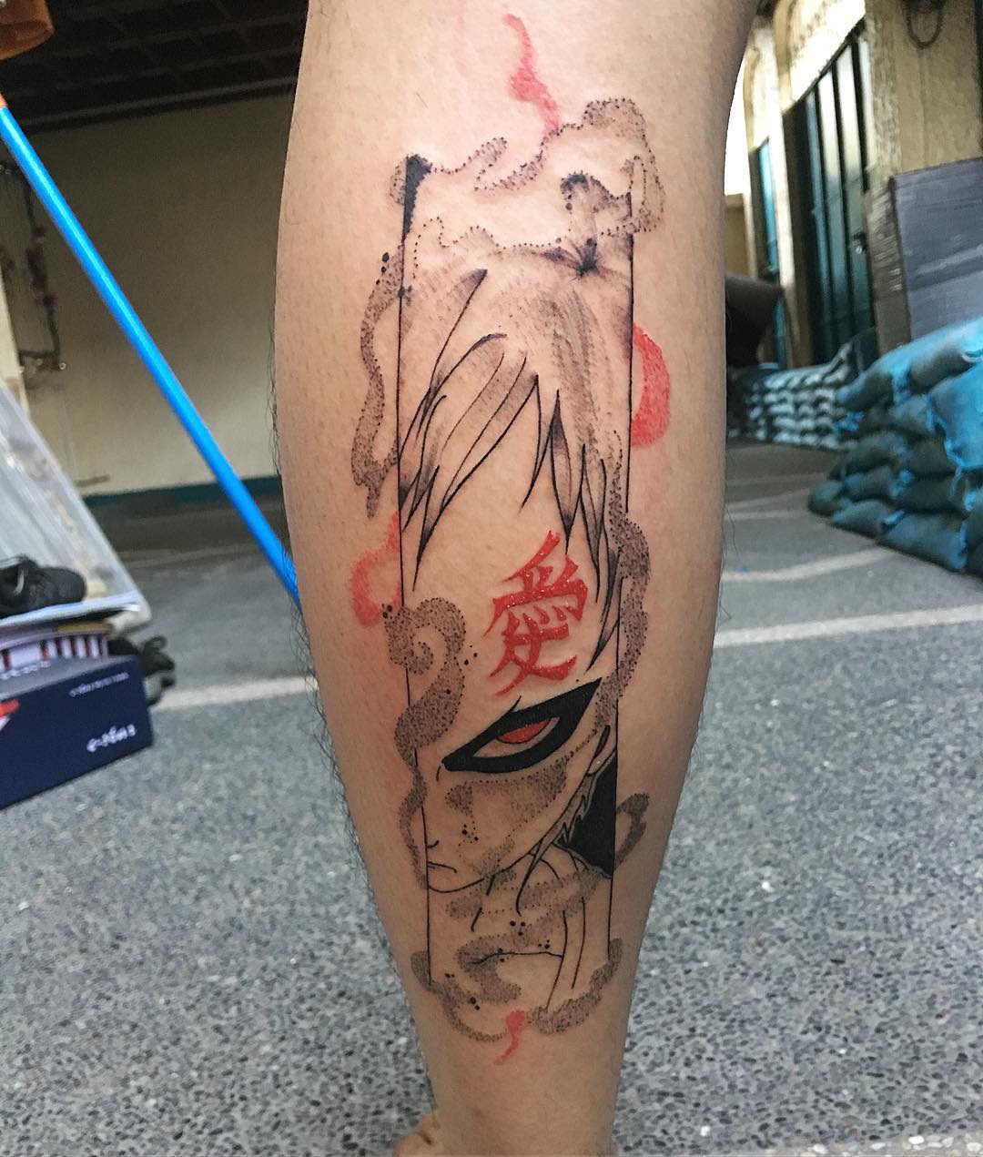 Leg tattoo featuring a character with red eyes, a symbol on the forehead, and surrounded by smoke