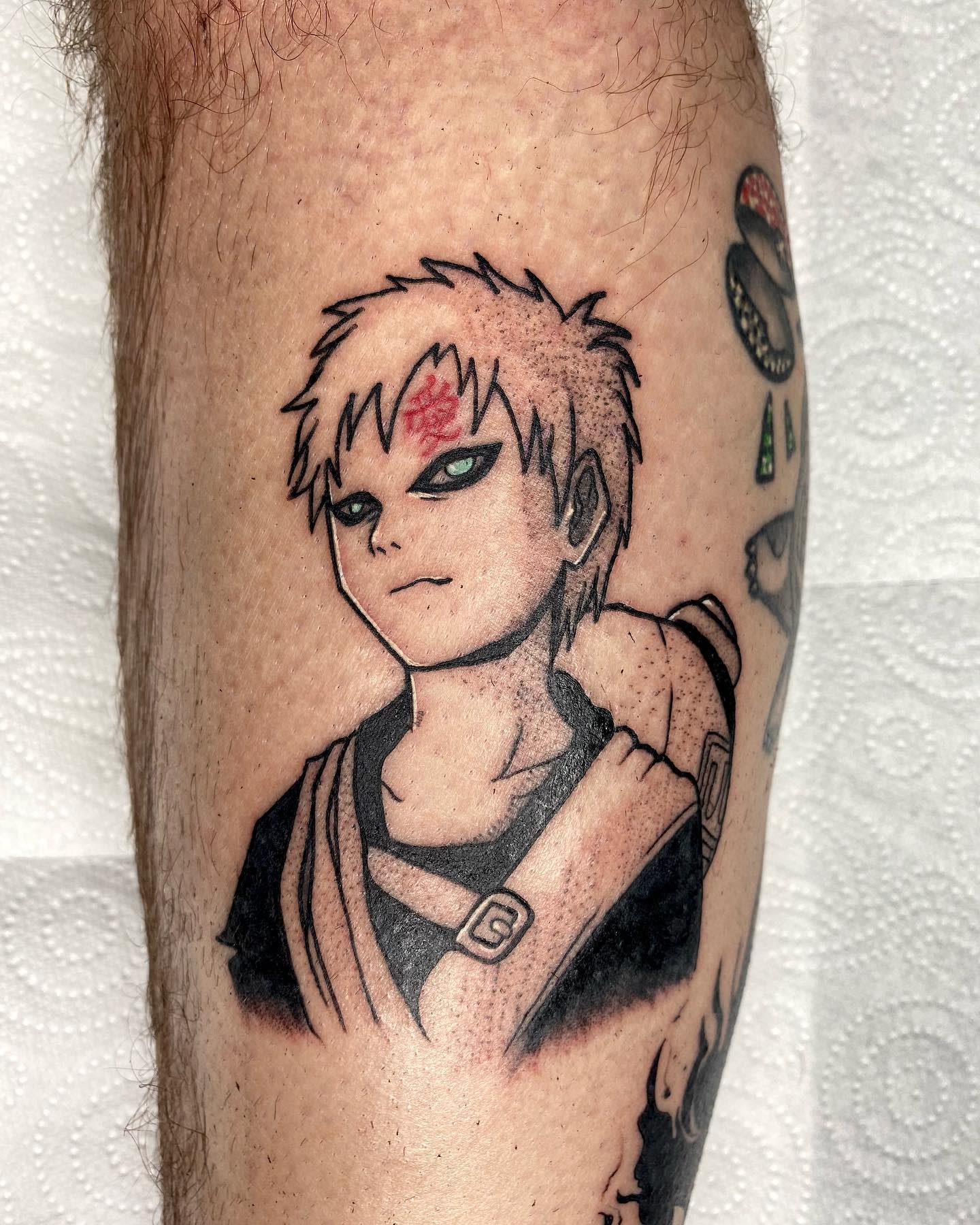 Tattoo of Gaara with spiky hair and a symbol on their forehead on a leg