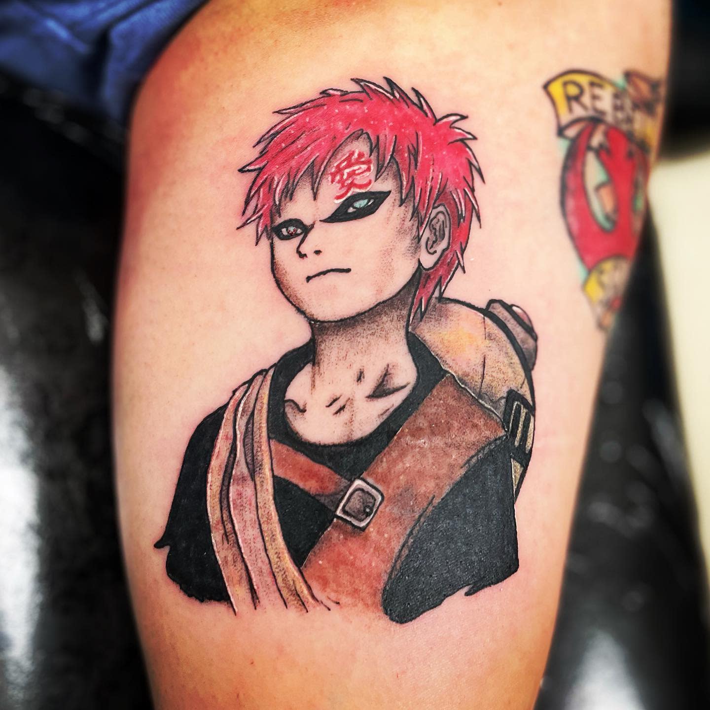 Thigh tattoo of Gaara with red hair wearing a black and brown outfit