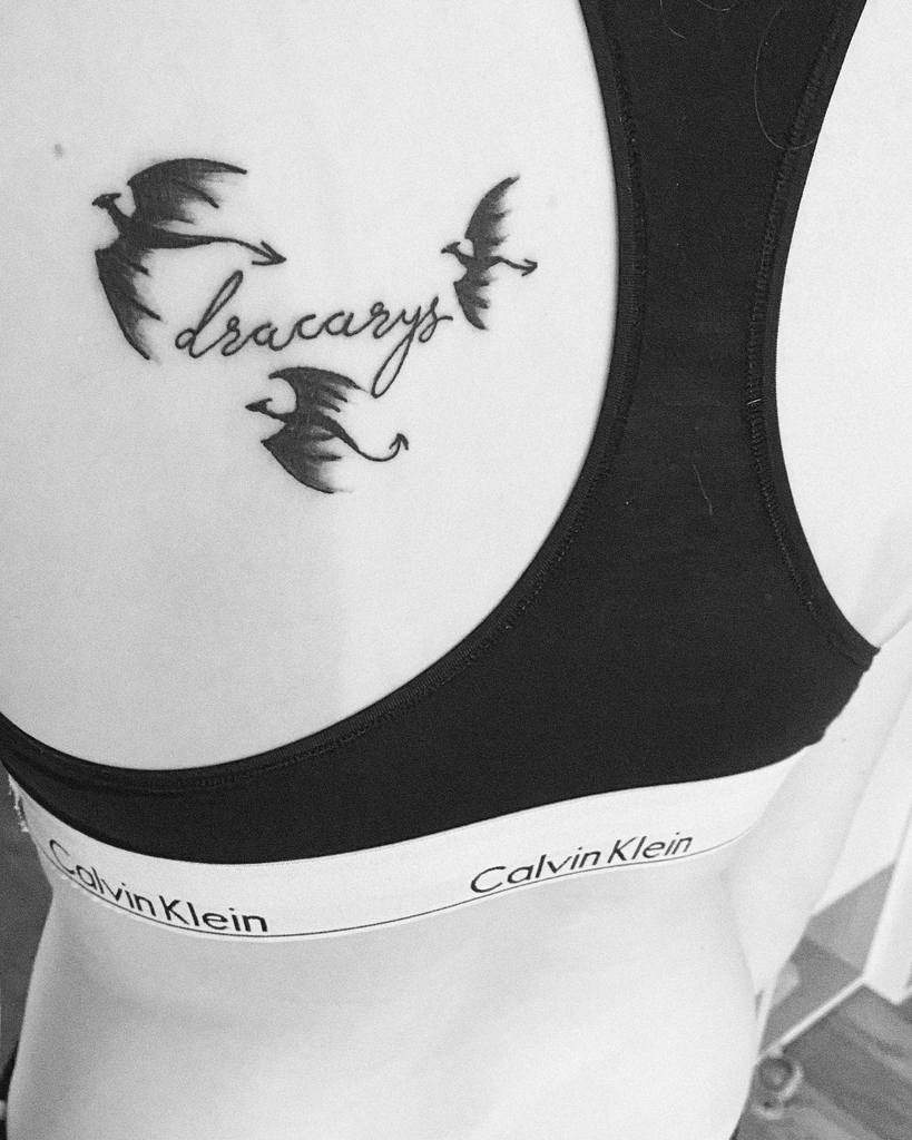 Game of Thrones-inspired back tattoo featuring three dragons in flight with the word 'Dracarys' in cursive font