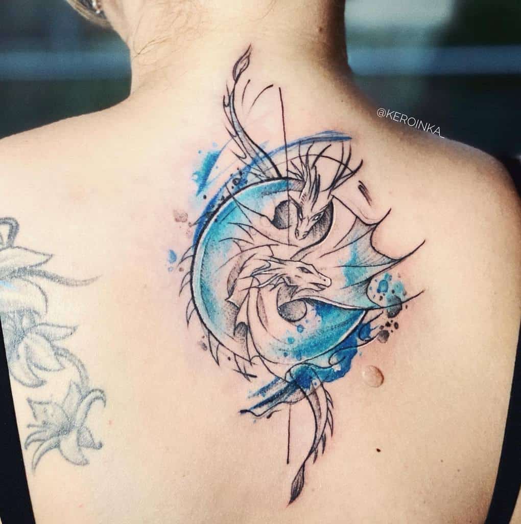 Artistic back tattoo featuring two dragons intertwined in a circular design with blue watercolor accents